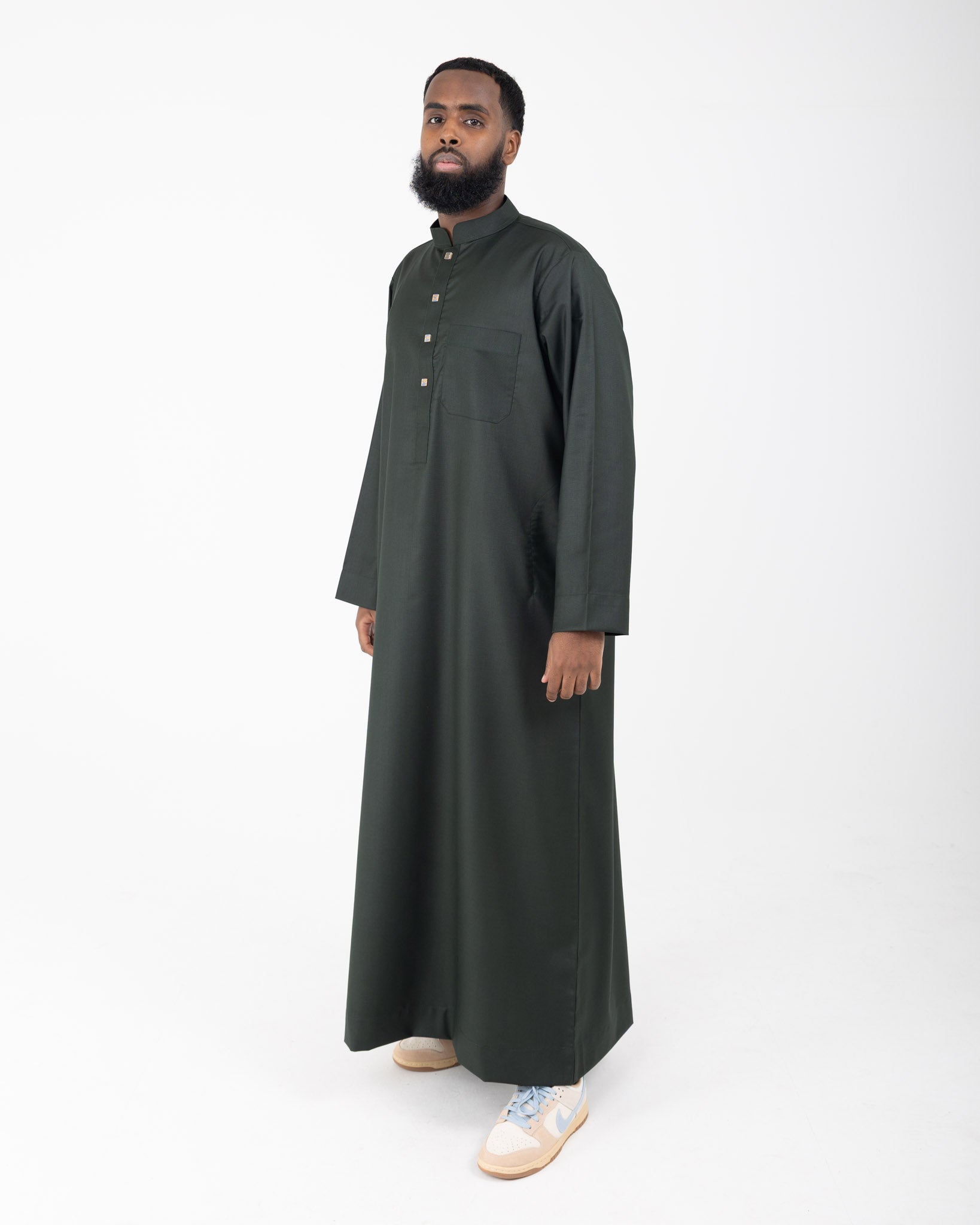 A man wearing a green long collared thobe with buttoned sleeves.