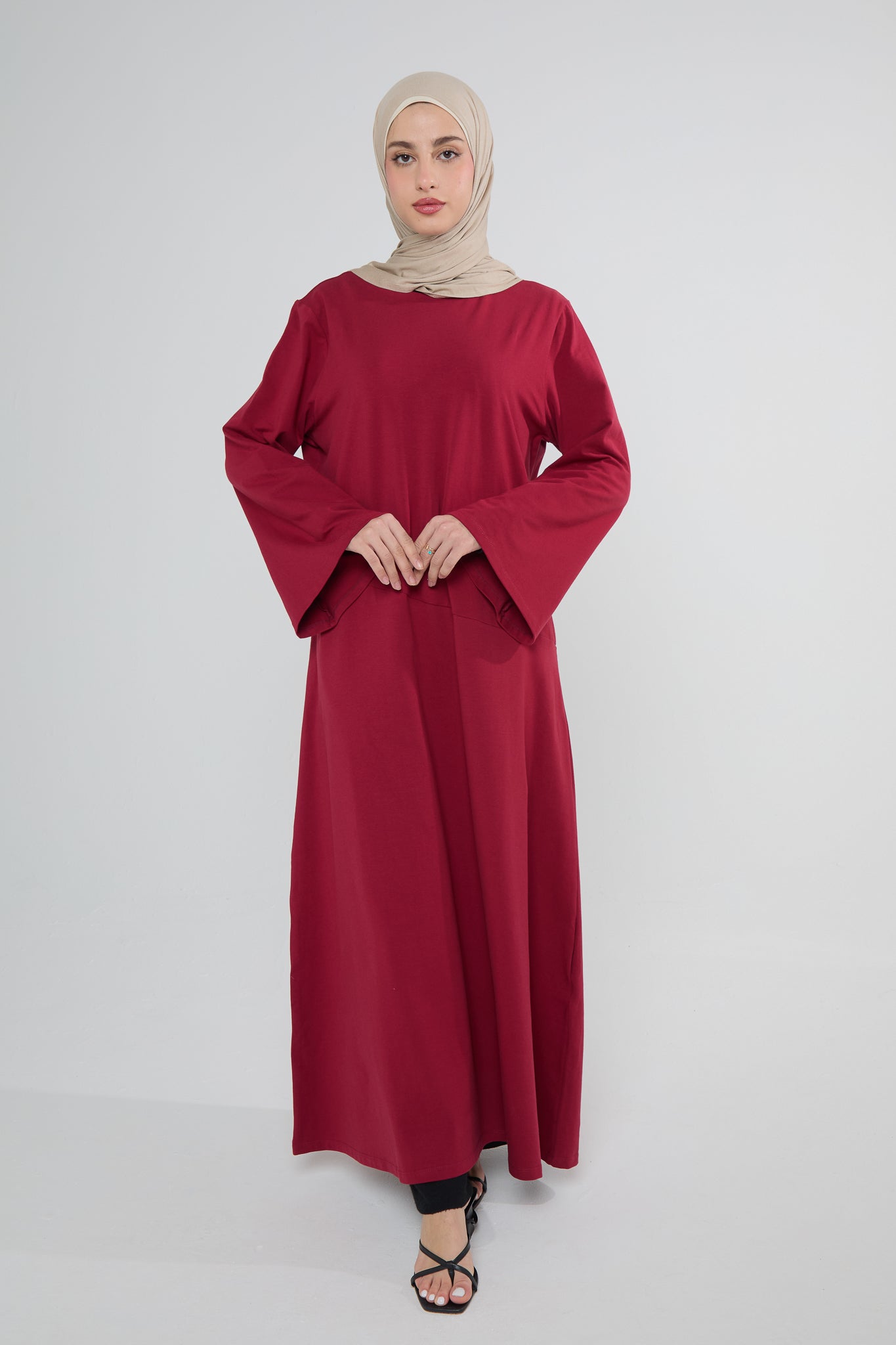 A woman wearing a red Mulberry Cotton Abaya Dress with a headscarf, posing against a white background.